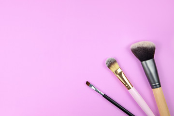 makeup brushes and cosmetics on pink background