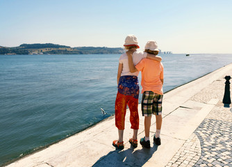 two children with hat see in the summer sun on the river Tejo