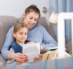 Positive young woman helping her daughter with home task