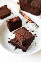 Sliced chocolate loaf cake served on two plates, a knife covered with chocolate, high key, white background