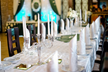 Silver candlestick with white candles on a decorated table.