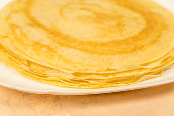 Ready-made rosy pancakes lie on a white plate close-up