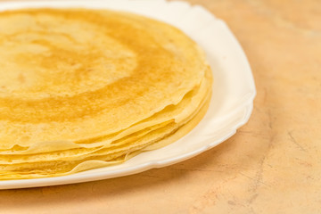 Ready-made rosy pancakes lie on a white plate close-up