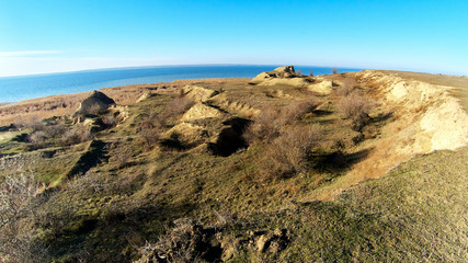 Clay rocks, a cliff on the shore of the lake. The hilly coast at sunny autumn day.