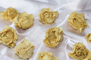 Dried rosebuds on a beige fabric. The fabric lies in waves. Autumn still life.