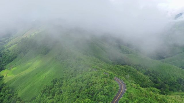 Aerial top view of sky road over top of mountain with fog and green jungle after raining in morning, Pua district, Nan province, Thailand.