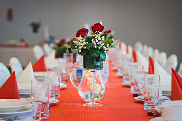 Kwiaty na stole z czerwonym obrusem i zastawą - obrazy, fototapety, plakaty
