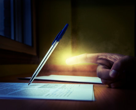 Hand with superpowers making a pen write on his own