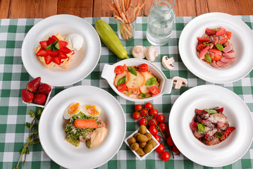 Meat with boiled eggs, lasagna, puff pastry strawberry dessert served on the table. Italian cousine concept.
