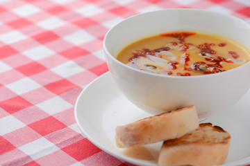 Hot and sour soup with shrimps and clams. Sea food soup with sauce served in a white bowl over light rustic wooden table
