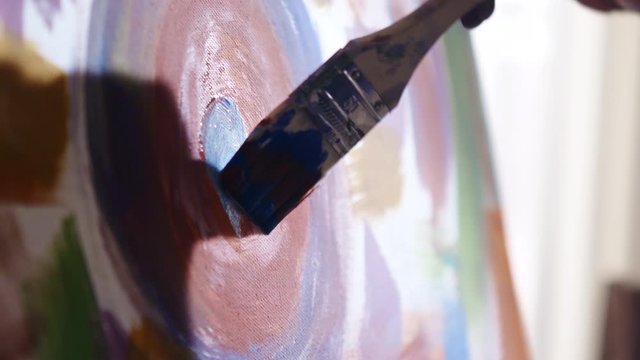 Abstract colorful painting on canvas created by black artist, using wide brush and bright colors, painting blue circle in the center of canvas, Close up, Slow motion.