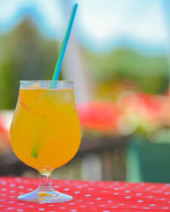 Mango mint lemon cocktail in a glass with plastic straw outside. Cold refreshing summer beverage.