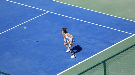 a girl hits the ball on a blue tennis court