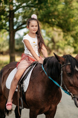 Fototapeta premium Emotional contact with the horse. Horse riding. The girl rides a horse in the summer.