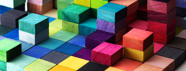 Spectrum of stacked multi-colored wooden blocks. Background or cover for something creative, diverse, expanding, rising or growing. Shallow depth of field. - obrazy, fototapety, plakaty