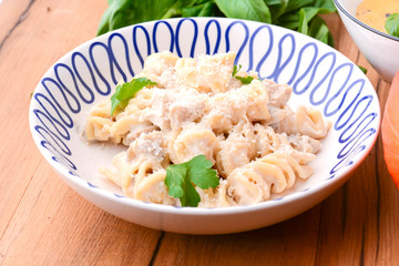 Italian pasta with grated cheese and rosemary served in white plate over wooden background.