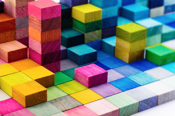Fototapeta na wymiar Spectrum of stacked multi-colored wooden blocks. Background or cover for something creative, diverse, expanding, rising or growing. 