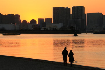 夕陽を前に砂浜を歩くカップル