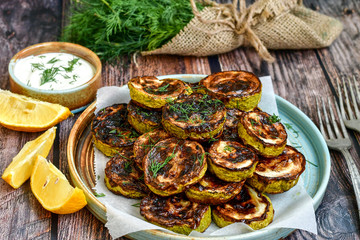 Home made  organic fried zucchini with  dill and  garlic yogurt sauce on wooden background