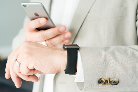 Ostfildern, Germany - May 14, 2015: A businessman is checking his Apple Watch while using his iPhone 6. The Apple Watch is the latest device by computer and smartphone manufacturer Apple Computer and