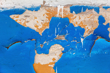 Surface of a concrete wall with old peeling multi-layer blue paint