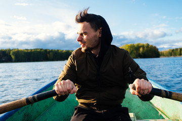 A man rowing on oars on an autumn lake