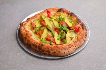 Close-up of a delicious smoked salmon pizza with cheese, avocado and smoked salmon. Sea-food. Textured gray background.