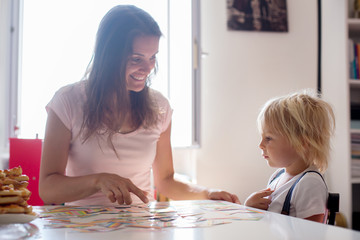 Mother, teaching her child toddler boy the alphabet and numbers, educating