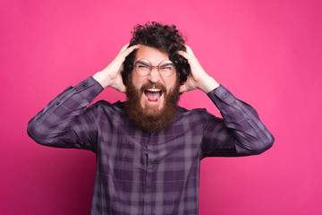 portrait of young bearded hipster man screaming and looking at the camera.