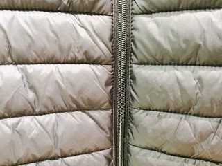 Close-up on grey puffer jacket texture with a zipper and a runner close-up © Galina