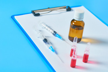 Different medicaments and clipboard with empty paper sheets on blue table. Doctor workplace. Examination in medical university. Diagnosing disease. Workspace in office of medicine supplier
