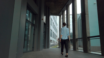 Business Woman walking the stairs of business center holding laptop. Successful woman works at prestige office. Female worker in office suit
