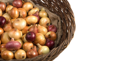 Half of the basket is filled with yellow and red onions lying on a linen bag, top view, Panorama. An isolated object. Vegetable background. Concept of food, farm products.