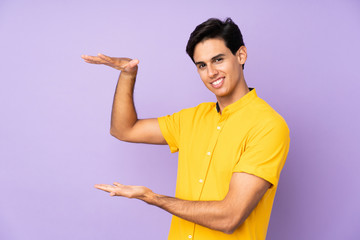 Man over isolated purple background holding copyspace to insert an ad