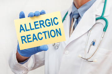Close-up of a male doctor holding a sign with the text Allergic Reaction