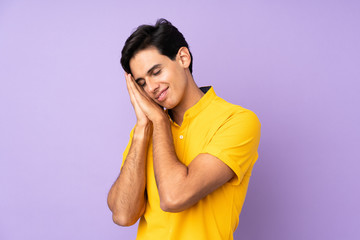 Man over isolated purple background making sleep gesture in dorable expression