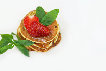 fluffy golden pancakes with strawberries and syrup on white background with copy space
