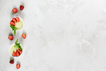 Homemade avocado panna cotta with strawberries, mint and coconut. Sugar, lactose, gluten free. Healthy food, diet, vegetarian. Horizontal orientation, copy space, top view.