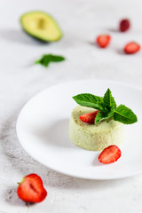 Homemade avocado panna cotta with strawberries and mint. Sugar, lactose, gluten free.