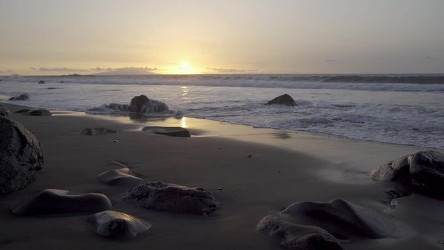 Wellen im Sonnenuntergang am schwarzen Sandstrand mit einzelnen gro&szlig;en Steinen - Playa del Ingles, Valle Gran Rey, La Gomera