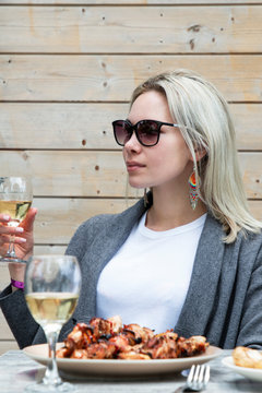 beautiful girl drinking white wine at the table with kebab