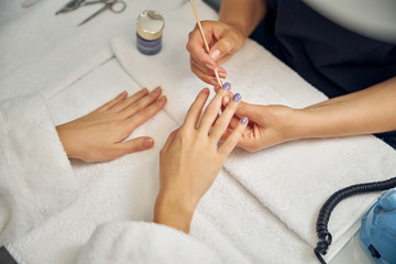 Beauty professional doing colour manicure for lady