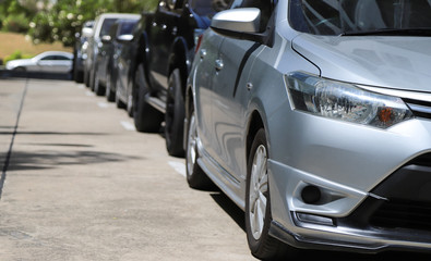 Fototapeta premium Closeup of front side of blue car with other cars parking in outdoor parking area in sunny day. 