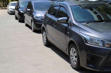 Closeup of front side of black car with  other cars parking in outdoor parking area in sunny day. 
