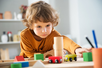 Little boy sits at a table and plays with the constructor