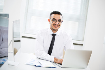Fototapeta na wymiar Happy arab businessman smiling while looking at camera in office