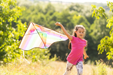 little girl running outdoor with a kite