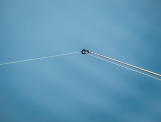 A monofilament fishing line on a fishing rod ring against blue water.