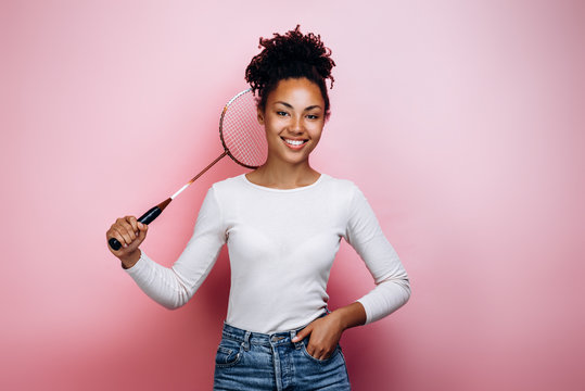 Girl holding a badminton racket on a background of a pink wall