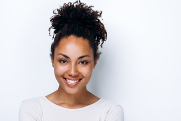 Close-up view of a cute girl smiling, cute posing on a white wall background